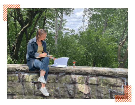 Ana Cazor écrit sur un muret avec la tour télé de Berlin en arrière plan